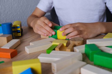 Çocuk, çocuk renkli ahşap figürlerden kuleler ve binalar inşa ediyor, konut inşaatı konsepti, mortgage, sigorta, mutlu çocukluk, çocuk oyunları