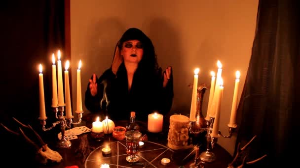 女性幸运女神在黑暗的房间里神仙 蜡烛在圆圆的 神秘的桌子上燃着 有五芒星 动物的骷髅躺着 魔法的概念 — 图库视频影像