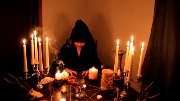 暗い部屋に女性のフォーチュンテラー神は ろうそくの五角形 動物の頭蓋骨 魔術の概念を横に丸い密教テーブルの上で燃焼している — ストック動画