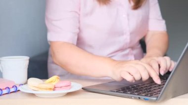 Şişman kadın bilgisayarın başına oturur ve internette sörf yapar, dizüstü bilgisayarın yanında makarnalı bir tabak, diyet konsepti, yüksek kalorili beslenme, kilo kaybı problemleri, vücut pozitifliği vardır.