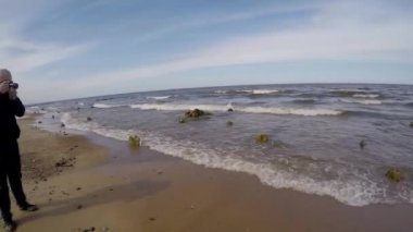 Güzel deniz manzarası, beyaz köpüklü mavi dalgalar kıyıya vuruyor, erkek fotoğrafçı fotoğraf çekiyor, konsept tatil, seyahat, ekoloji, çevre koruma