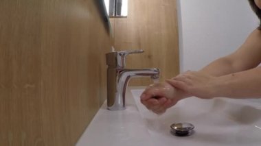 Su krom kaplamalı musluktan ince bir dere gibi akar, kız ellerini yıkar, sağlıklı yaşam biçimi, temizlik, sağlık...