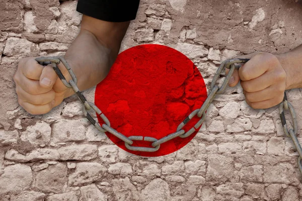 male hands breaking the iron chain, symbol of bondage, protest against the background of the state flag of Japan, the concept of political repression, tyranny, arrest, crime, civil rights, freedom