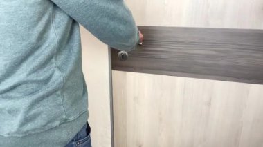 Gri kazaklı ve kot pantolonlu genç adam ofiste, evde, otel odasında, iş seyahati, turizm, işyeri konsepti, açık kapı açıyor.