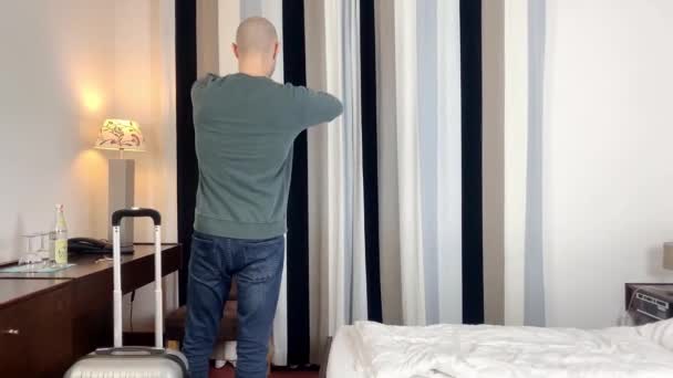 Νεαρός Άνδρας Στέκεται Μπροστά Από Παράθυρο Ανοίγει Τις Κουρτίνες Κοιτάζει — Αρχείο Βίντεο