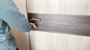 Gri kazaklı ve kot pantolonlu genç adam ofiste, evde, otel odasında, iş seyahati, turizm, işyeri konsepti, açık kapı açıyor.