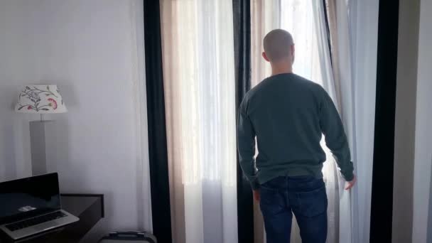 Młody Człowiek Stoi Przed Oknem Otwiera Zasłony Patrzy Ulicę Pojęcie — Wideo stockowe