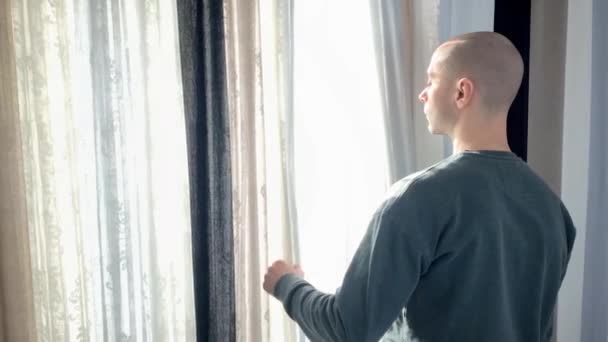 Jeune Homme Tient Devant Fenêtre Ouvre Les Rideaux Regarde Rue — Video