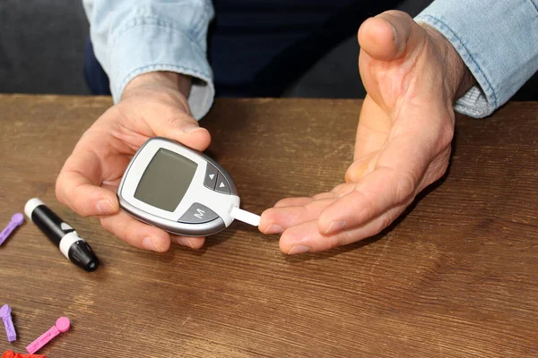 Close-up Of A Man\'s Hand Checking Blood Sugar Level With Glucometer, medical concept, control of blood glucose, diabetes