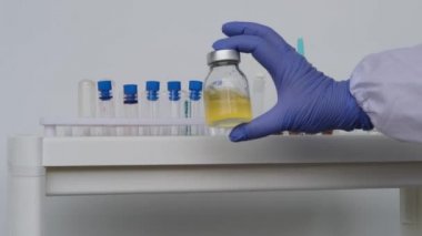 Doktor, bilim adamı, laboratuvar asistanı, bir şişe sıvı, araştırma aşısı, yeni ilaç, modern bilimde yenilik kavramı, COVID-19 için tedavi, test, bilim ve geleceğin tıbbı.