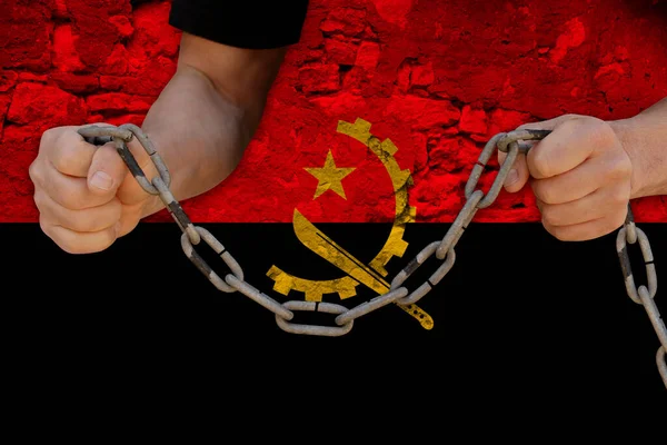 male hands breaking the iron chain, symbol of bondage, protest against the background of the state flag of Angola, the concept of political repression, tyranny, arrest, crime, civil rights, freedom