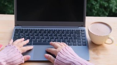 Yaz bahçesinde, kadın blogcu dizüstü bilgisayarda yazı yazıyor, boş ekranlı bilgisayar, tasarımcı için siyah ekran, bir fincan cappuccino, programcının işyeri konsepti, blog yazma