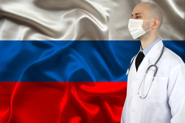 male doctor with a stethoscope on the background of the silk national flag of Russia, concept of national medical care, health, insurance, tourism
