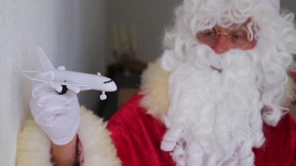 飛行機 クリスマスのコンセプトを保持している白いひげを持つサンタクラスは 贈り物 新年のお祝い 冬休み 航空旅行を待っています — ストック動画