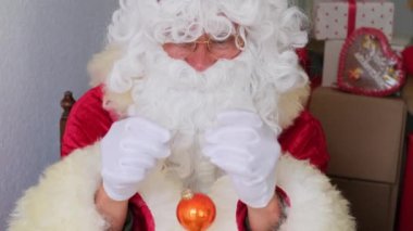 Kırmızı takım elbiseli beyaz sakallı Noel Baba Noel ağacını toplarla süslüyor. Hediye bekleyen konsept, yeni yılı kutlayan, tatil satışları, Nicholas Günü.