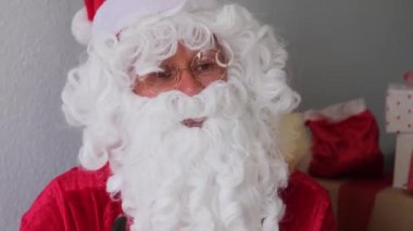 Beyaz sakallı Noel Baba mutlu yıllar diler, satışlar ve indirimlerden bahseder, Noel konsepti, hediyeleri beklemek, neşeli bir ruh hali.