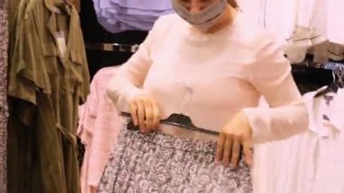 Kadın alışverişler yapıyor, mağazadaki askılarda aynı kıyafetleri giyiyor moda, alışveriş, mevsimlik satışlar, tüketici malları için yüksek fiyatlar.