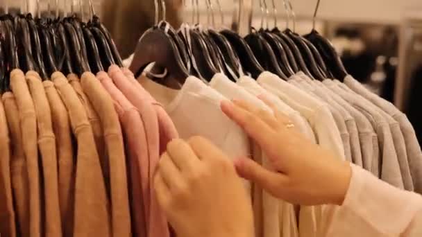 Kobieta Dokonuje Zakupów Przechodzi Przez Szereg Identycznych Ubrań Wieszakach Sklepie — Wideo stockowe