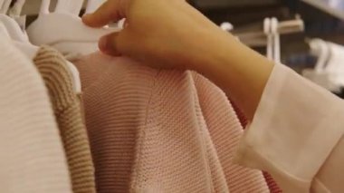Kadın alışverişler yapıyor, mağazadaki askılarda aynı kıyafetleri giyiyor moda, alışveriş, mevsimlik satışlar, tüketici malları için yüksek fiyatlar.