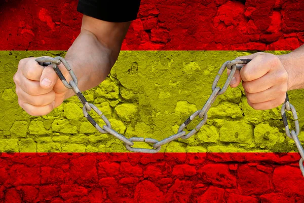 male hands breaking the iron chain, symbol of bondage, protest against the background of the state flag of Spain, the concept of political repression, tyranny, arrest, crime, civil rights, freedom