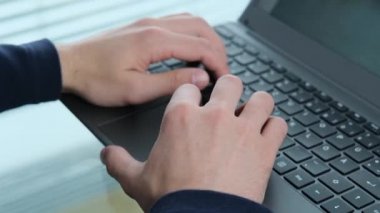 Genç adam, modern bir Avrupa şehrinin penceresinin önündeki bir ofiste dizüstü bilgisayarın arkasında çalışıyor. İş fikirleri kavramı, işyeri.