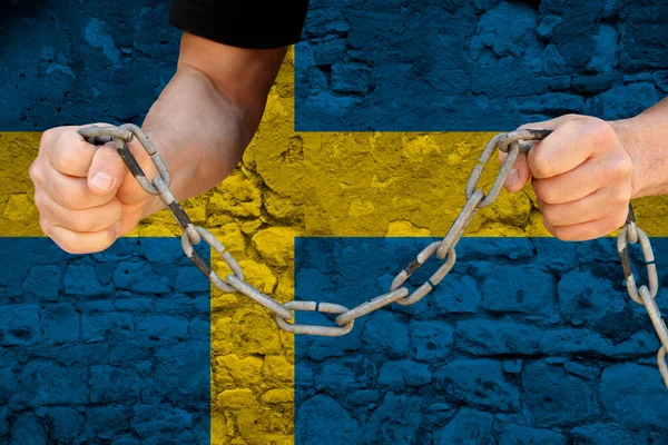 male hands breaking the iron chain, symbol of tyranny, protest against the background of the national flag of Sweden, the concept of political repression, arrest, crime, civil rights, freedom
