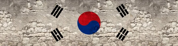 seamless panorama of the national flag of the state of South Korea on an old stone wall with cracks, the concept of tourism, emigration, economy, politics, civil rights and freedoms