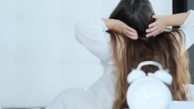 Uzun saçlı genç bir kadın sabah yatağında, evinde ya da otelinde uyanıyor. Sağlıklı uyku, uykusuzluk, tatil, iyi ruh hali, kadın mutluluğu kavramı.