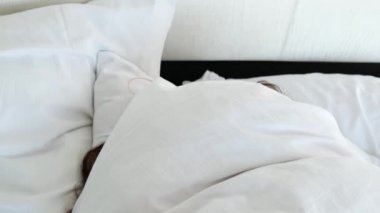 Uzun saçlı genç kadın evde ya da otelde yatakta derin uykuda. Sağlıklı uyku, uykusuzluk, tatil, iyi ruh hali, kadın mutluluğu kavramı.
