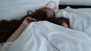 Uzun saçlı genç kadın evde ya da otelde yatakta derin uykuda. Sağlıklı uyku, uykusuzluk, tatil, iyi ruh hali, kadın mutluluğu kavramı.