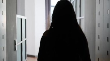 Uzun saçlı, zarif elbiseli genç bir kadın otel odasına giriyor, tekerlekli bavul taşıyor, pencereye geliyor, tatil konsepti, seyahat...