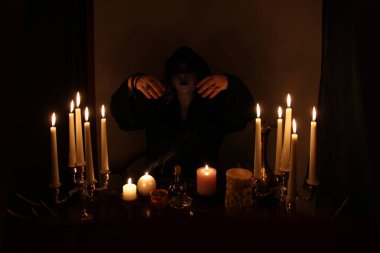 Dişi falcı karanlık bir odada, mumlar pentagramla yuvarlak bir masada yanıyor, hayvan kafatasları yalan söylüyor, sihir kavramı, cadılık kavramı...