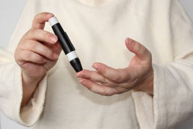 Yakın plan kadın elleri, kadın tükenmez kalem ve glukometreyle test yapıyor, tıbbi konsept, kan şekeri kontrolü, diyabet.