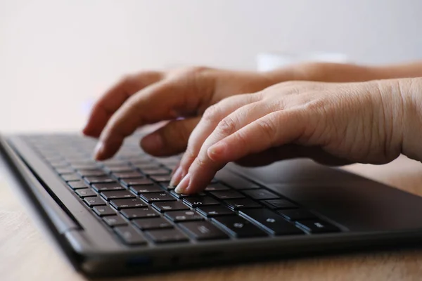 woman is typing on laptop keyboard, selective focus, working in evening at laptop of his house, hands closeup, concept of remote work, quarantine, downshifting