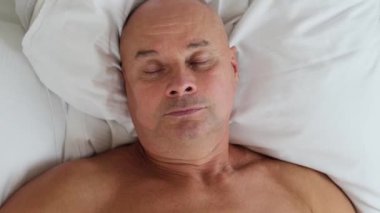 Yaşlı adam beyaz yatakta uyuyor, iş seyahati konsepti, seyahat, sağlıklı uyku, uykusuzluk, gürültü...