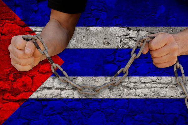 male hands breaking the iron chain, symbol of tyranny, protest against the background of the national flag of Cuba, the concept of political repression, arrest, crime, civil rights, freedom