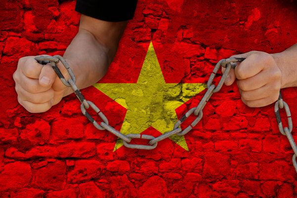 male hands breaking the iron chain, symbol of tyranny, protest against the background of the state flag of Vietnam, the concept of political repression, arrest, crime, civil rights, freedom
