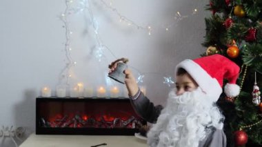 Küçük çocuk, Noel Baba yardımcısı, beyaz sakallı bir elf noel ağacının yanında oturuyor, yeni yıl konsepti, hediyeleri bekliyor, çocukluk, şenlik havası