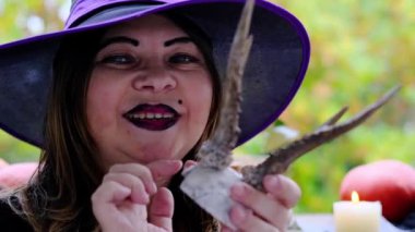 Siyah bir koçandaki cadı kurbanlık hayvanın boynuzlarıyla kafatasının üzerinden sihirli geçişler yapıyor. Cadılar Bayramı konsepti, aşk büyüsü, kehanet, parti hazırlığı.