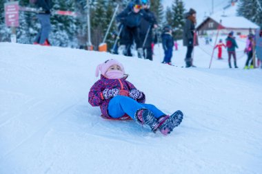 Parkta denge kirişinde yürüyen çocuk, açık hava ekipmanlarında dengede duran küçük kız, yeşil çimen arka planı, açık hava oyunu, koordinasyon egzersizi, renkli kazak ve kot giyen çocuk, aktif yaşam tarzı. 