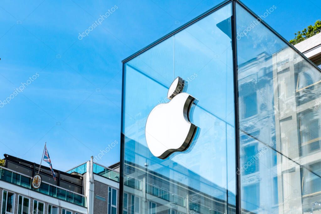 White Apple store logo on transparent glass storefront, iPhone, iMac company branding, modern brand business, tech branding, urban environment, Milan, Italy - May 21, 2025
