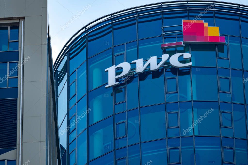 PwC logo on glass facade, high-rise glass office building against blue sky, finance and consulting, global economy, professional financial services in Germany, Frankfurt - February 9, 2025