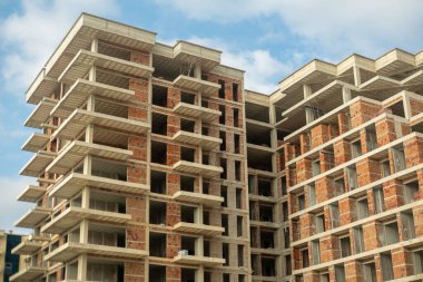 Tamamlanmamış Modern apartman, inşaat tuğlası ve beton yapı altındaki yüksek binalar kentsel gelişim, boş pencereler, balkonlar, berrak mavi gökyüzü, modern şehir genişlemesi