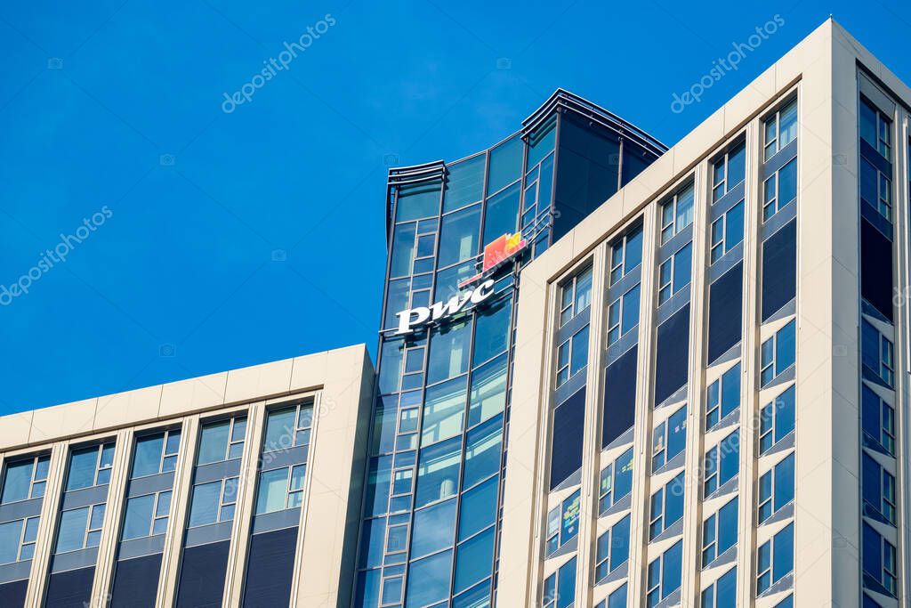 PwC logo on glass facade, high-rise glass office building against blue sky, finance and consulting, global economy, professional financial services in Germany, Frankfurt - February 9, 2025