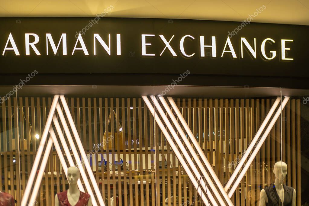 Armani Exchange fashion store front with illuminated signage wooden slats and modern interior design, Mannequins display fashion lifestyle products in Tirana, Albania - September 10, 2025