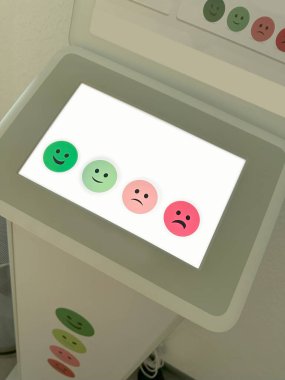 Olumlu geri bildirim sağlamak için memnuniyet anketi kioskunu kullanan mutlu çalışan, dokunmatik ekran, insan-bilgisayar etkileşimi, geri bildirim mekanizması hakkında olumlu değerlendirme yapar