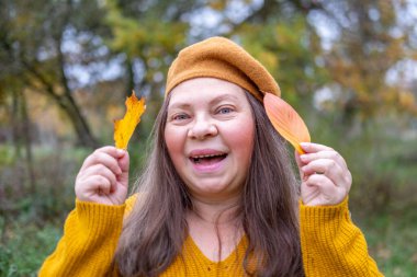 Sonbahar sarı yapraklı olumlu olgun bir kadın doğayı, sonbahar mevsimini kutluyor, temiz havanın tadını çıkarıyor, açık hava portresi, pozitif enerji, doğal arka plan, rahat tarz.