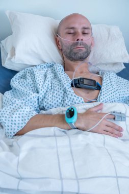 Genç adam, uyku apnesi izleme cihazı ve parmak ucu nabız oksimetresi, erkek hasta takip cihazı, ergen uyku çalışma ekipmanları, gençlik solunum bozukluğu araştırma konsepti