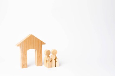 Çocuklu genç bir aile bir ahşap evin yakınına duruyor. Güçlü bir aile, ailenin devamı kavramı. Uygun fiyatlı konut satın almak için kredi. Aile için yeni bir ev