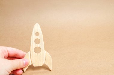 Beyaz bir arka plan üzerinde ahşap roket elinde. Bir adam bir roket ile oynuyor. Minimalizm, uzay seyahat ve Turizm, ticari roket uzaya başlattı. Diğer gezegenlerin fethi.